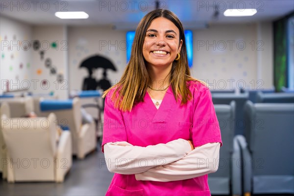 Portrait of a happy nurse standing with arms crossed in a geriatric