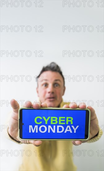 Crazy man holding mobile phone with Cyber Monday advertisement on the screen. Copy space on vertical shot