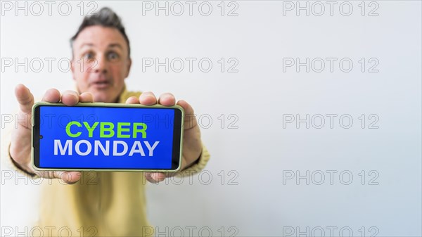 Crazy man holding mobile phone with Cyber Monday advertisement on the screen. Copy space