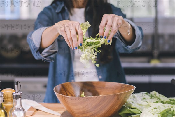 A woman preparing a green salad in her kitchen