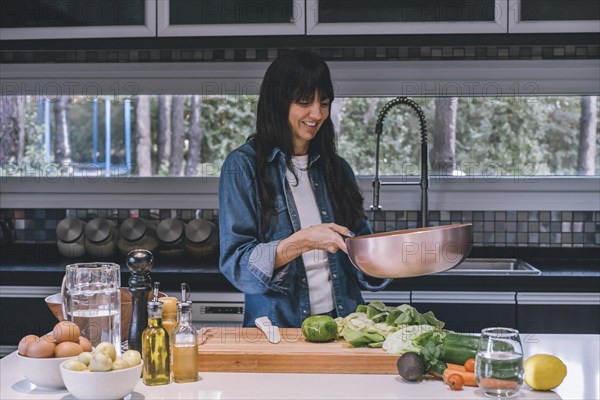 A woman cooking vegetables in a copper wok