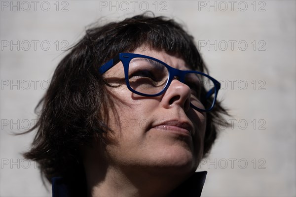 Headshot on a Elegant Woman with Eyeglasses and Leaning on a Concrete Wall in a Sunny Day in Switzerland