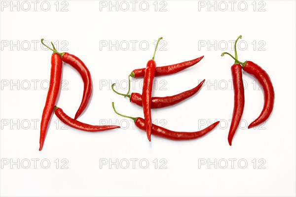 Red chilli peppers arranged to spell out RED HOT CHILI . The chillies are against a white background