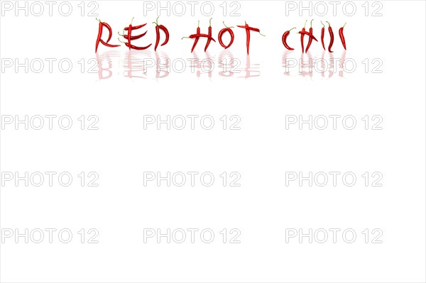 Red chilli peppers arranged to spell out RED HOT CHILI . The chillies are against a white background