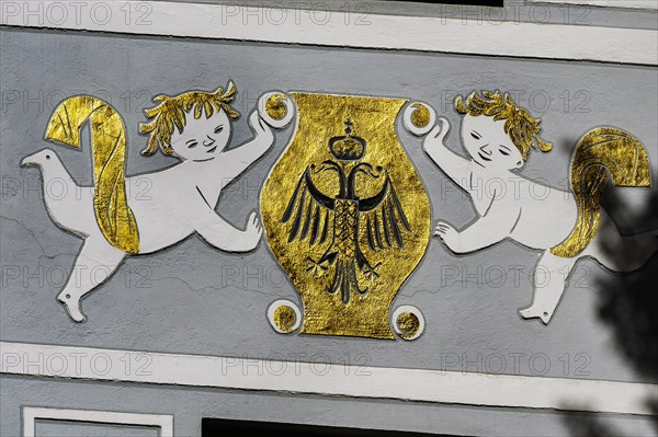 Fresco with golden coat of arms and double-headed eagle with crown on grey facade