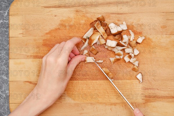 Close up overhead view of chopping shiitake on wooden cutting board