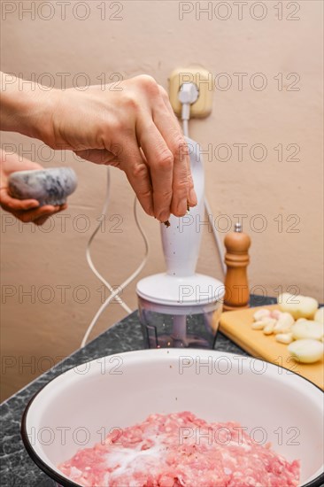 Hand of woman adding pepper to minced meat