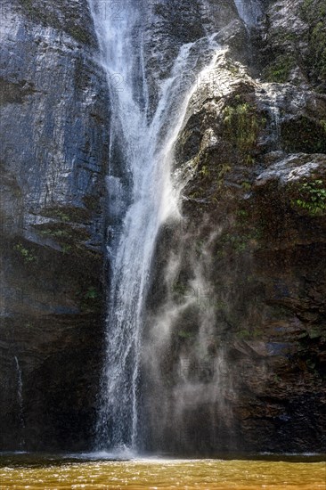 Waterfall water running down dark rocks lit by the sun in the state of Minas Gerais