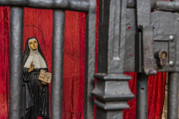 Model of a praying nun behind bars