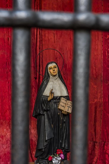 Model of a praying nun behind bars