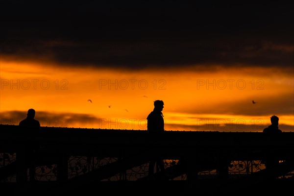 A passer-by crosses the Eiserner Steg in Frankfurt am Main at sunset