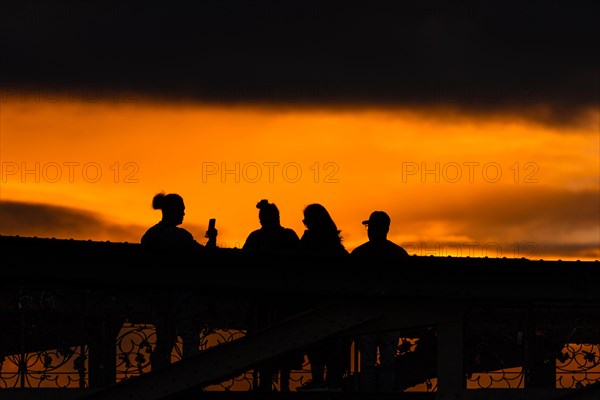 Passers-by watching and photographing the sunset from the Eiserner Steg in Frankfurt am Main