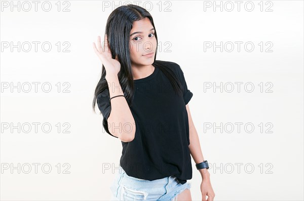 Young girl with hand on ear hearing a rumor isolated. Beautiful teenage girl listening to a rumor isolated