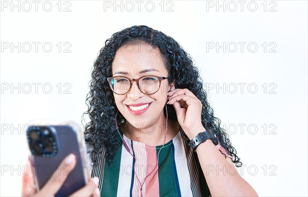 Close up of cheerful afro girl listening songs with celphone on isolated background. Young afro woman listening to music with headphones isolated