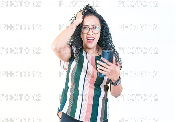 Worried young woman scratching head holding phone. puzzled woman in glasses holds cell phone