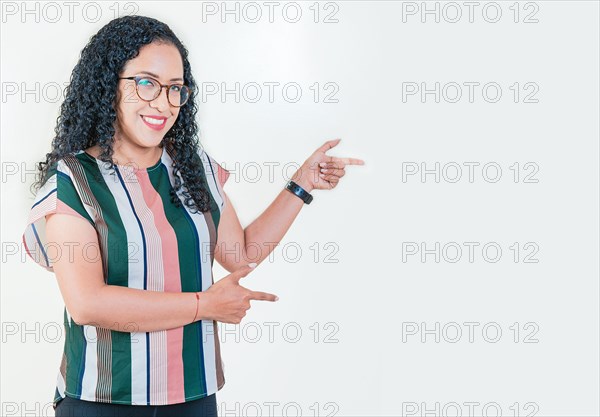 Happy young afro woman pointing a promotion at side. Cheerful afro girl pointing an offer isolated. Beautiful latin girl pointing to a banner to the side