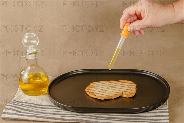 Woman pours olive oil on toast with an dropper because of excessive oil prices