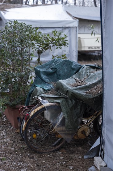 Rusty bicycles covered with a tarpaulin at an out-of-season campsite