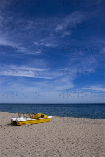 Yellow pedal boat on the beach with blue sky and blue sea