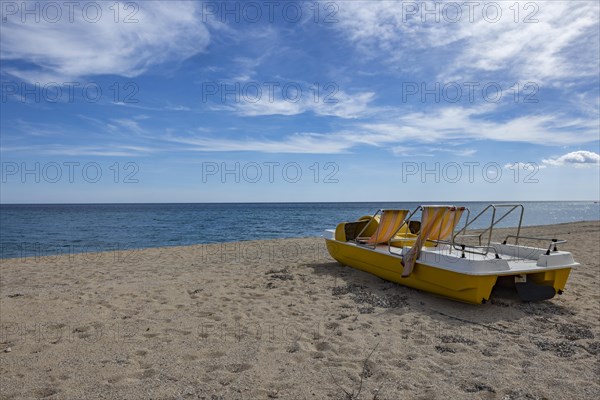 Yellow pedal boat on the beach with blue sky and blue sea