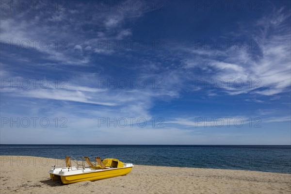 Yellow pedal boat on the beach with blue sky and blue sea