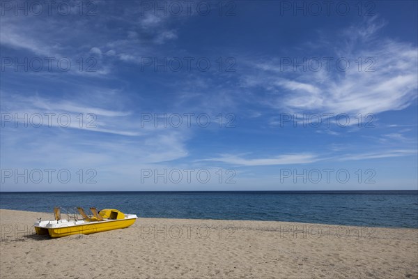 Yellow pedal boat on the beach with blue sky and blue sea