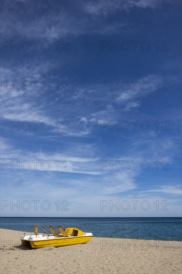 Yellow pedal boat on the beach with blue sky and blue sea