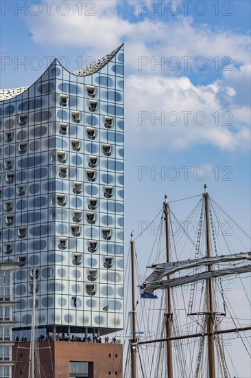 Mast of a sailing ship in front of the façade of the Elbe Philharmonic Hall