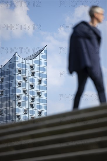 Silhouettes of people on the harbour promenade in front of the Elbe Philharmonic Hall