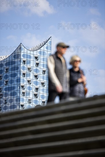 Silhouettes of people on the harbour promenade in front of the Elbe Philharmonic Hall