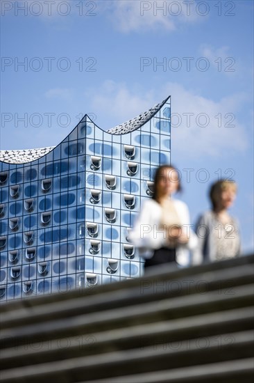 Silhouettes of people on the harbour promenade in front of the Elbe Philharmonic Hall