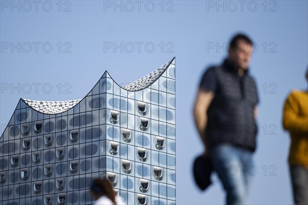 Silhouettes of people on the harbour promenade in front of the Elbe Philharmonic Hall