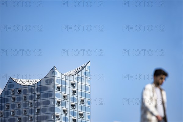 Silhouettes of people on the harbour promenade in front of the Elbe Philharmonic Hall