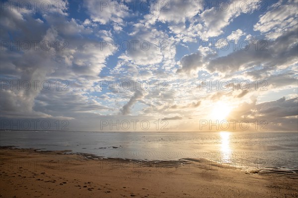 Sunrise on the sandy beach. Landscape shot with a view of the sea and the beach. Waves of light and a morning atmosphere that only exists in Sanur