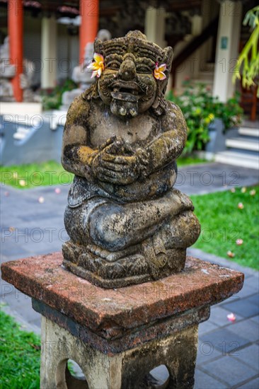 Park with tropical plants and traditional statues of the Hindu faith and for decoration. Tropical island life as a tourist on Bali