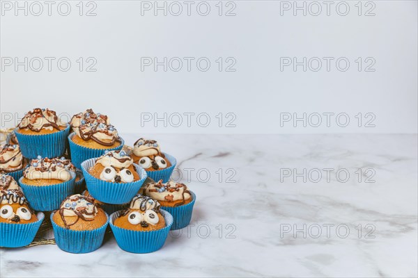 Muffins in blue ramekins with chocolate icing and sugar sprinkles