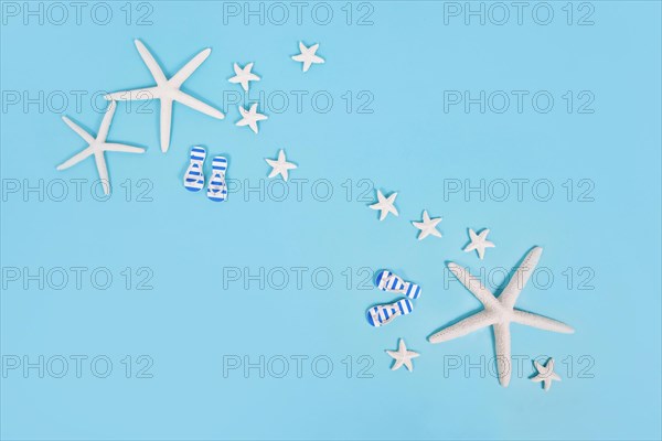 Simple summer banner with white starfish and sandals on blue background