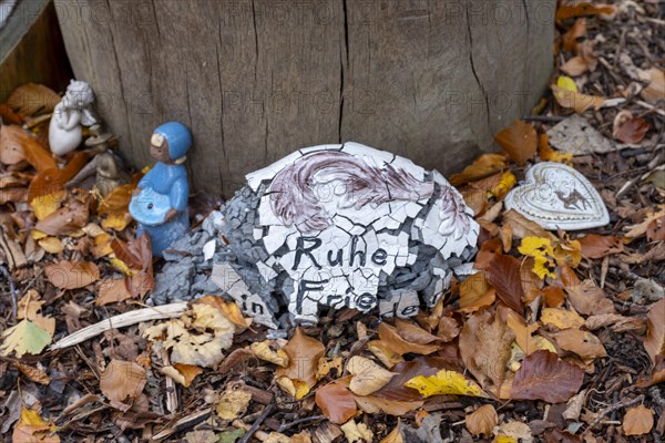 Mementos and stones in the shape of a heart on a memorial tree with the names of the buried