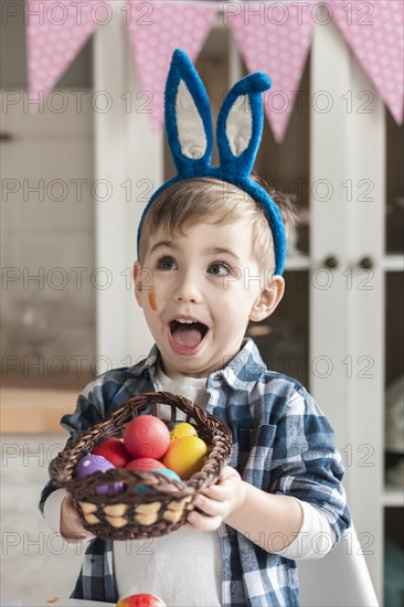 Adorable little boy holding basket with easter eggs
