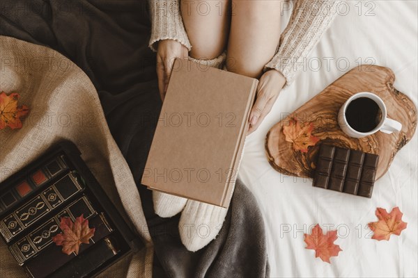 Anonymous woman with book near tea chocolate