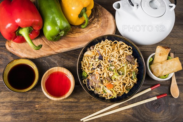 Bell peppers udon noodles sauces spring rolls white desk