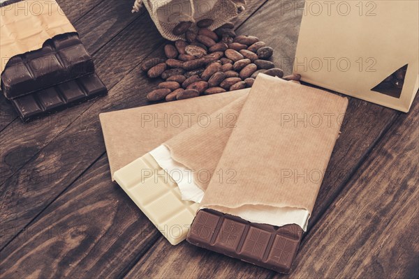 Broken package dark milk chocolate bar with cocoa beans table