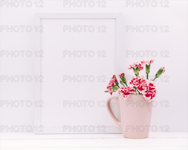 Carnation flowers vase with empty frame table