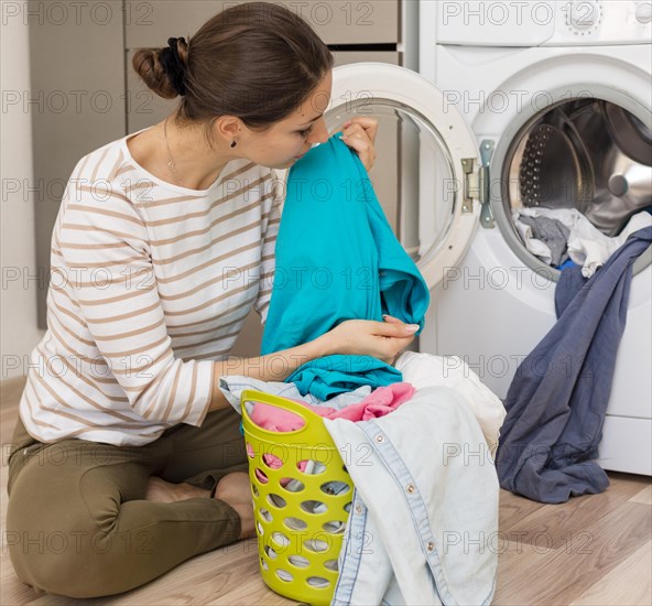 Casual woman smelling clean laundry