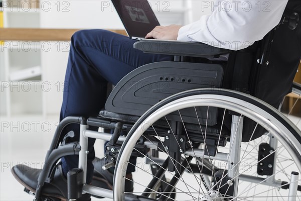 Close up businessman sitting wheelchair using laptop