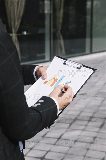 Close up business person s hand drawing increasing arrow graph clipboard