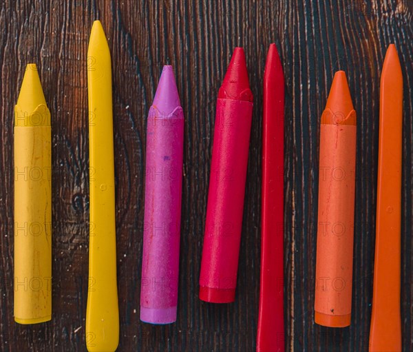 Close up colorful wax crayons wooden textured plank