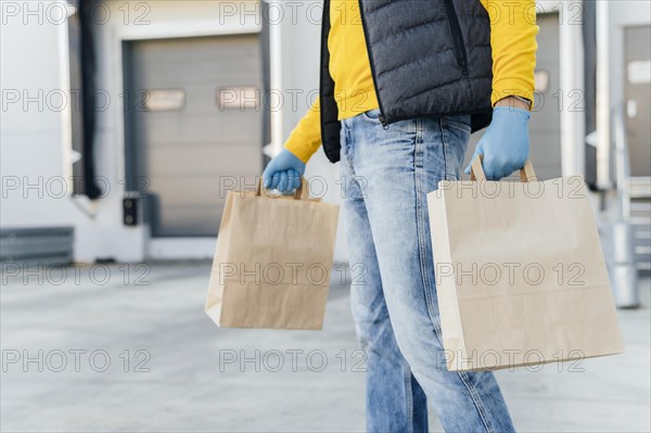 Close up delivery man holding paper bags