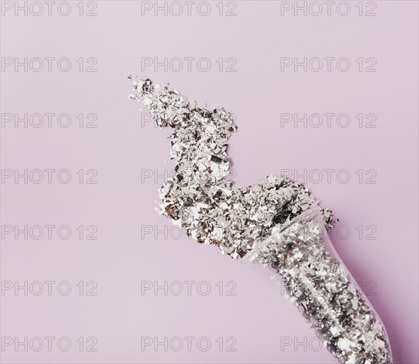 Close up glass champagne filled with silver glitter copy space violet background