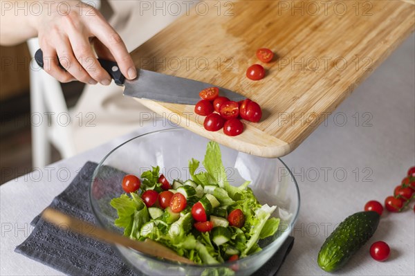 Close up hand putting tomatoes salad